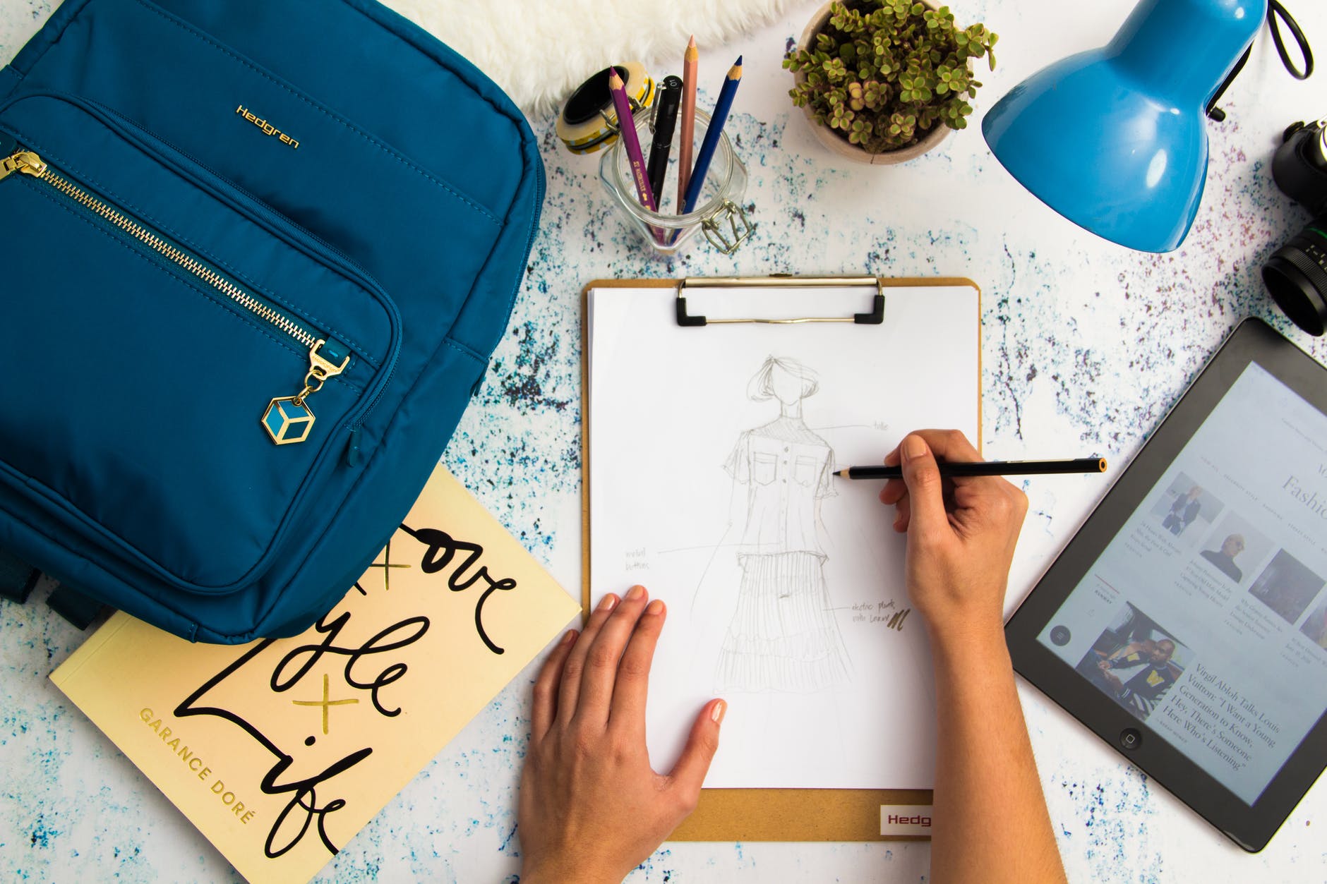 person sketching dress on printer paper with clip board